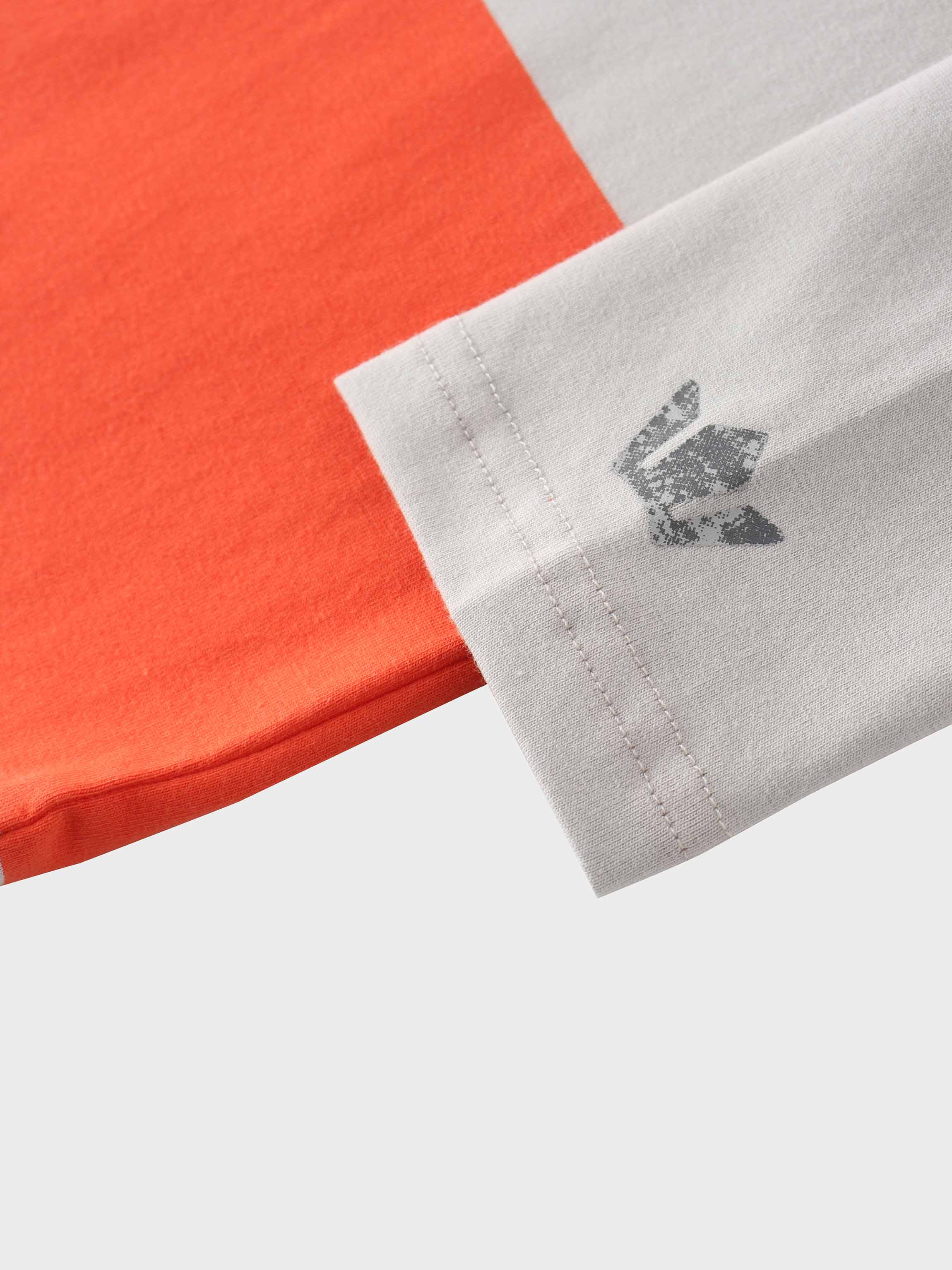 Close-up of orange and grey fabric, with a weathered silver logo on the grey part.