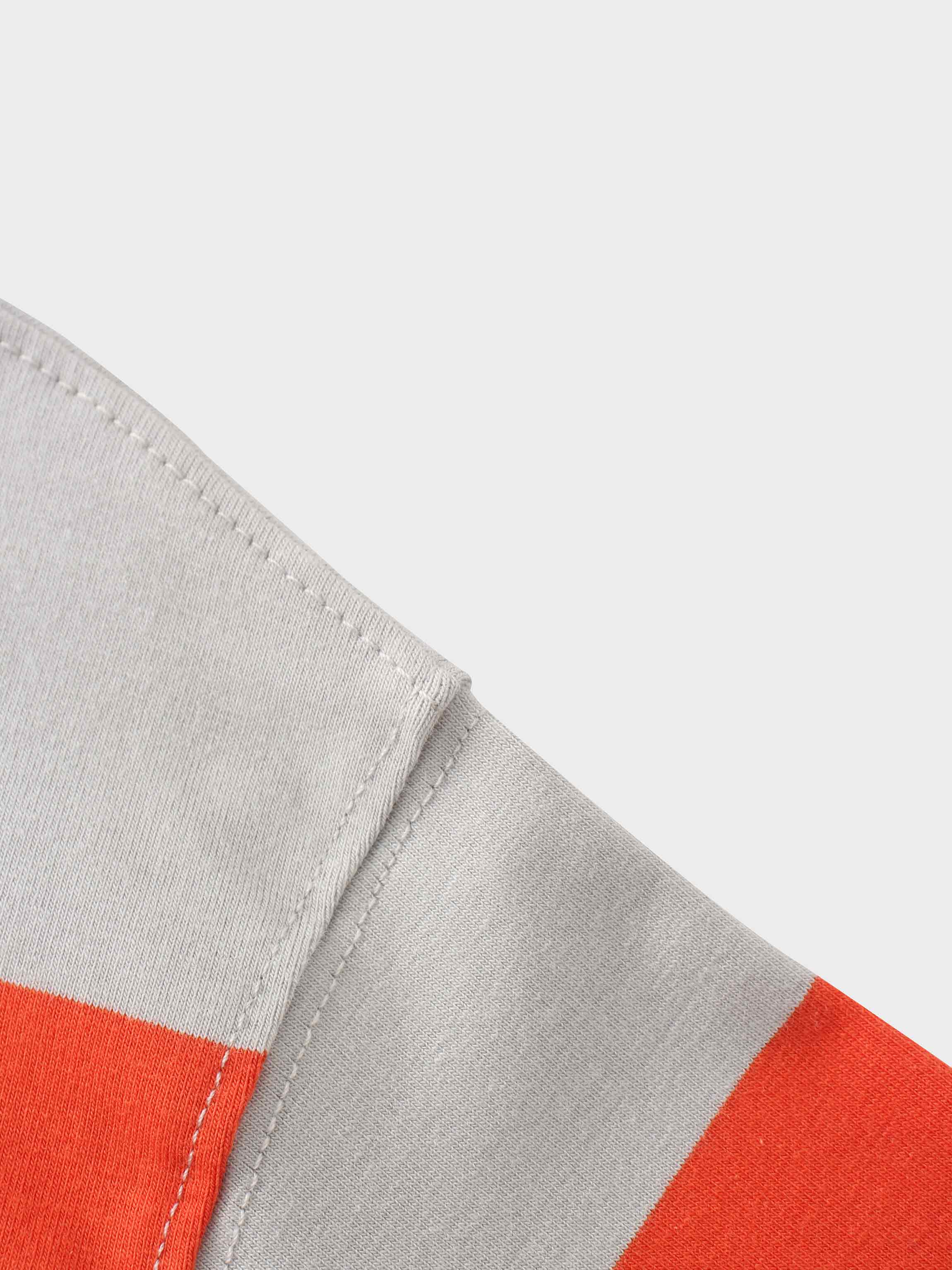 Detail of a seam on an orange and grey striped fabric.
