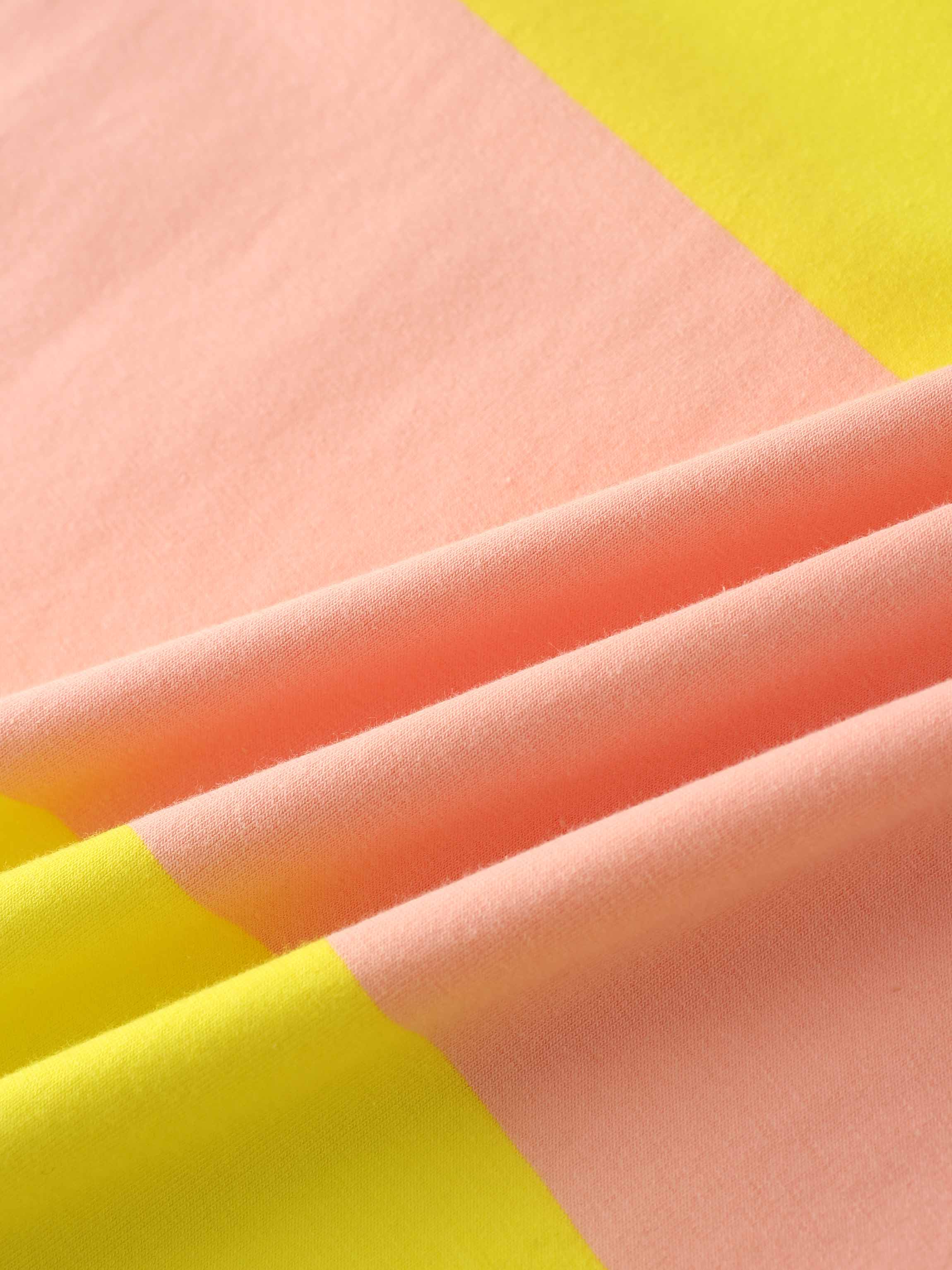 Yellow and peach-colored striped fabric with soft folds.