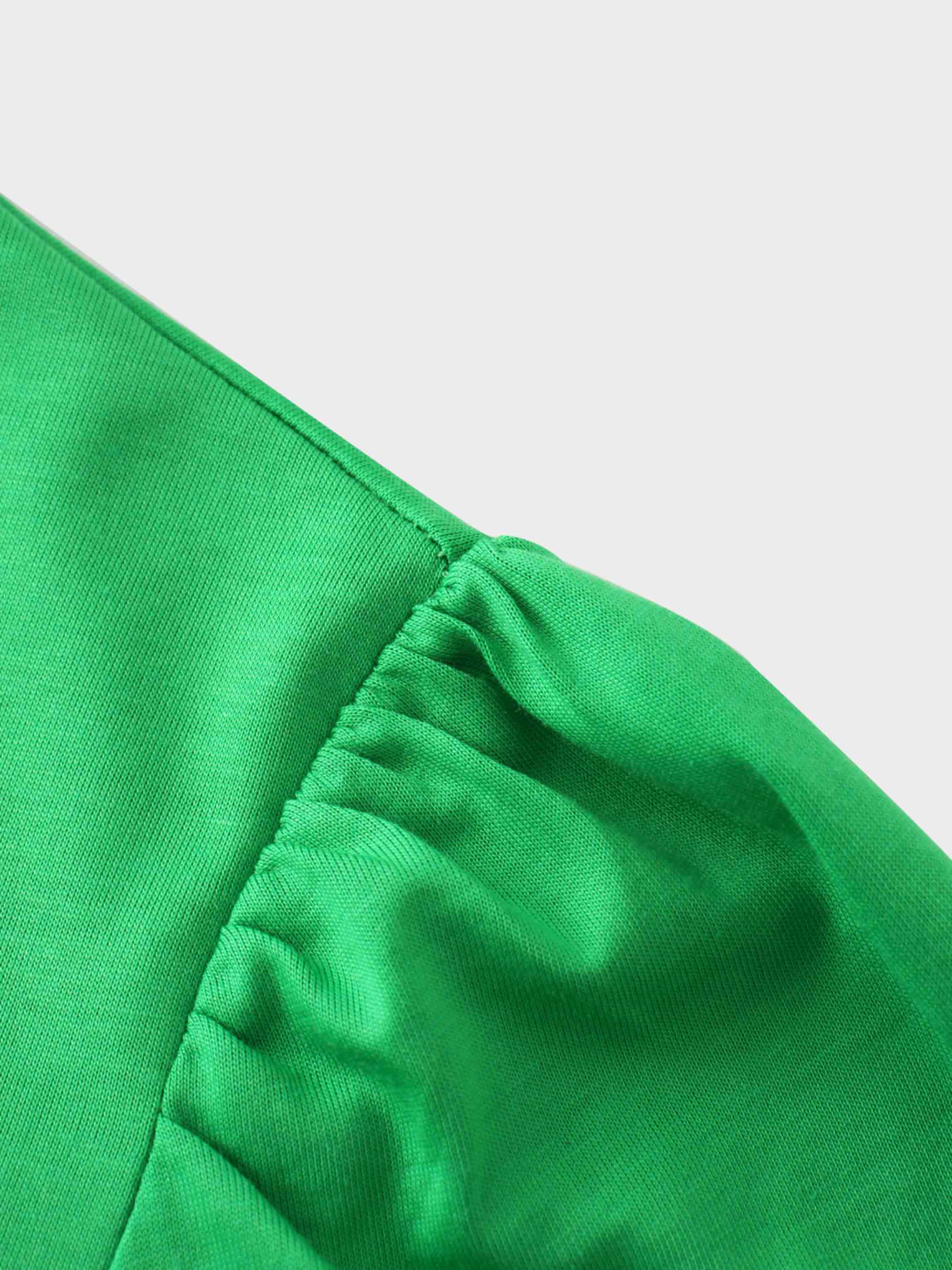 A close-up of the shoulder of the vibrant green shirt. The fabric at the top of the sleeve is gathered where it is sewn into the shoulder, creating a puff sleeve detail.
