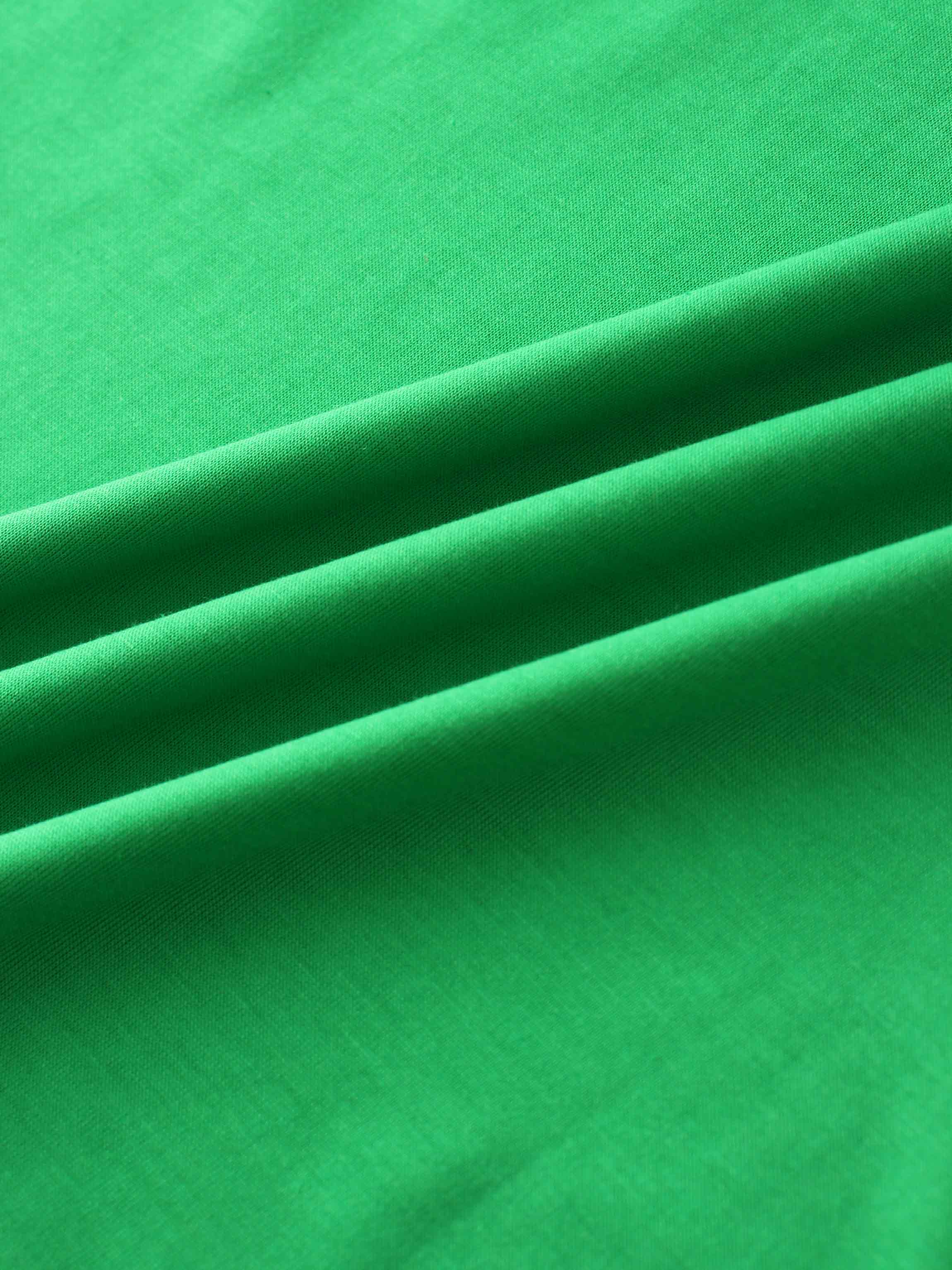 A close-up of a smooth fabric in a vibrant green color. The material is arranged in several soft, diagonal folds.