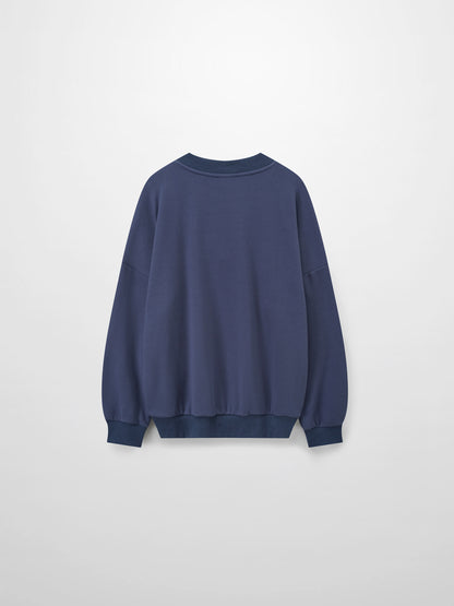 A full, back view of the dusty-blue sweatshirt. The image shows the plain back of the garment, along with its ribbed collar, cuffs, and bottom hem.