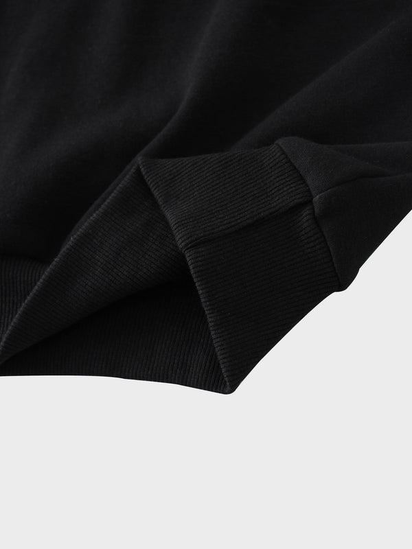 A full, front view of the black sweatshirt. The image shows the ribbed collar, cuffs, and hem, along with the subtle, black-on-black embroidered logo on the chest and a white tag inside the neckline.
