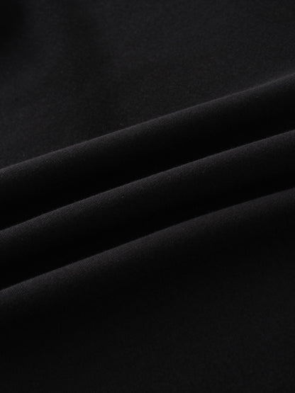 A close-up of a smooth, black fabric. The material is arranged in soft, diagonal folds, with lighting creating highlights on the creases.