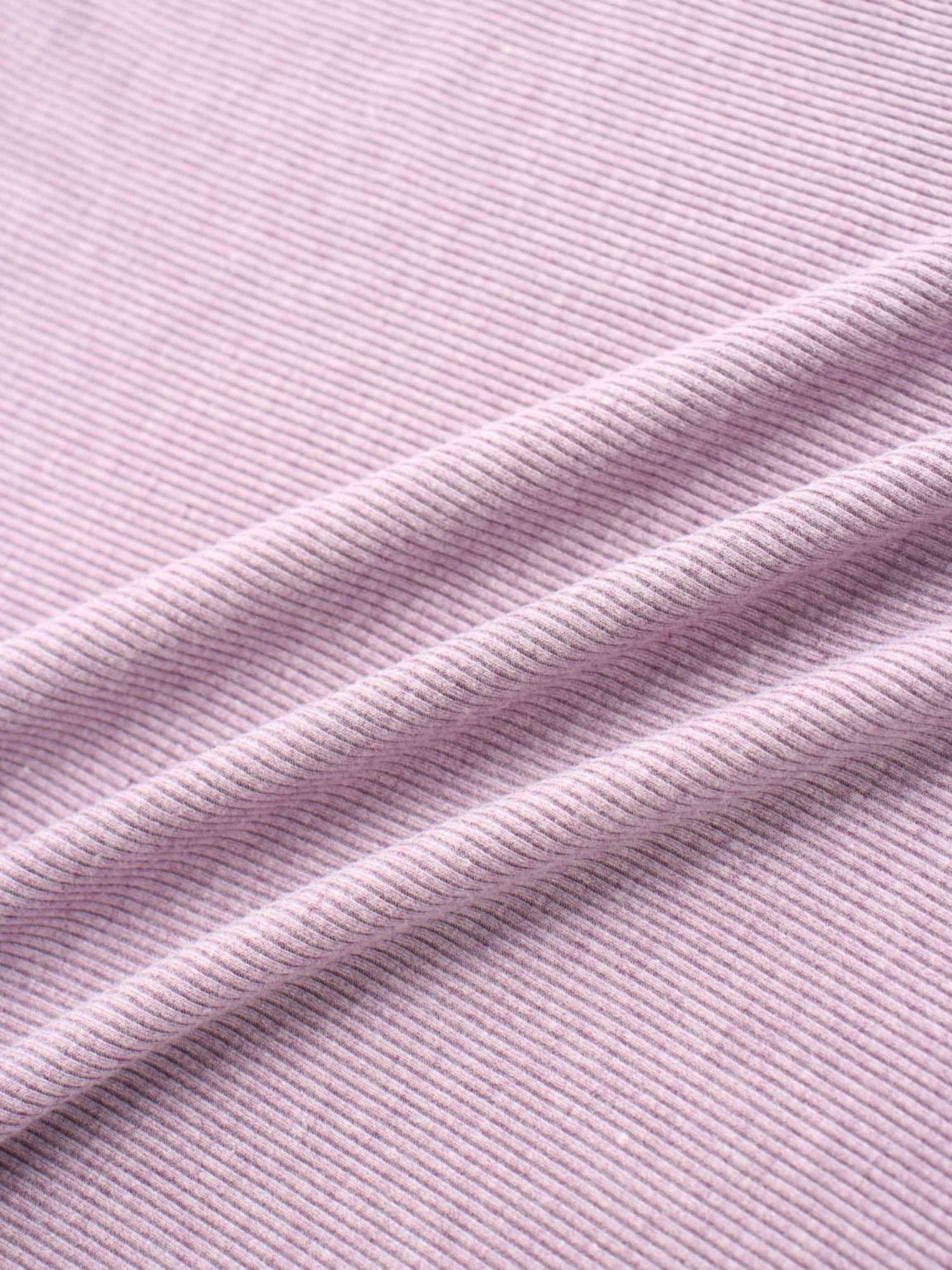 A soft, lavender-colored fabric with a finely ribbed texture. The material is folded, creating gentle diagonal lines and shadows.