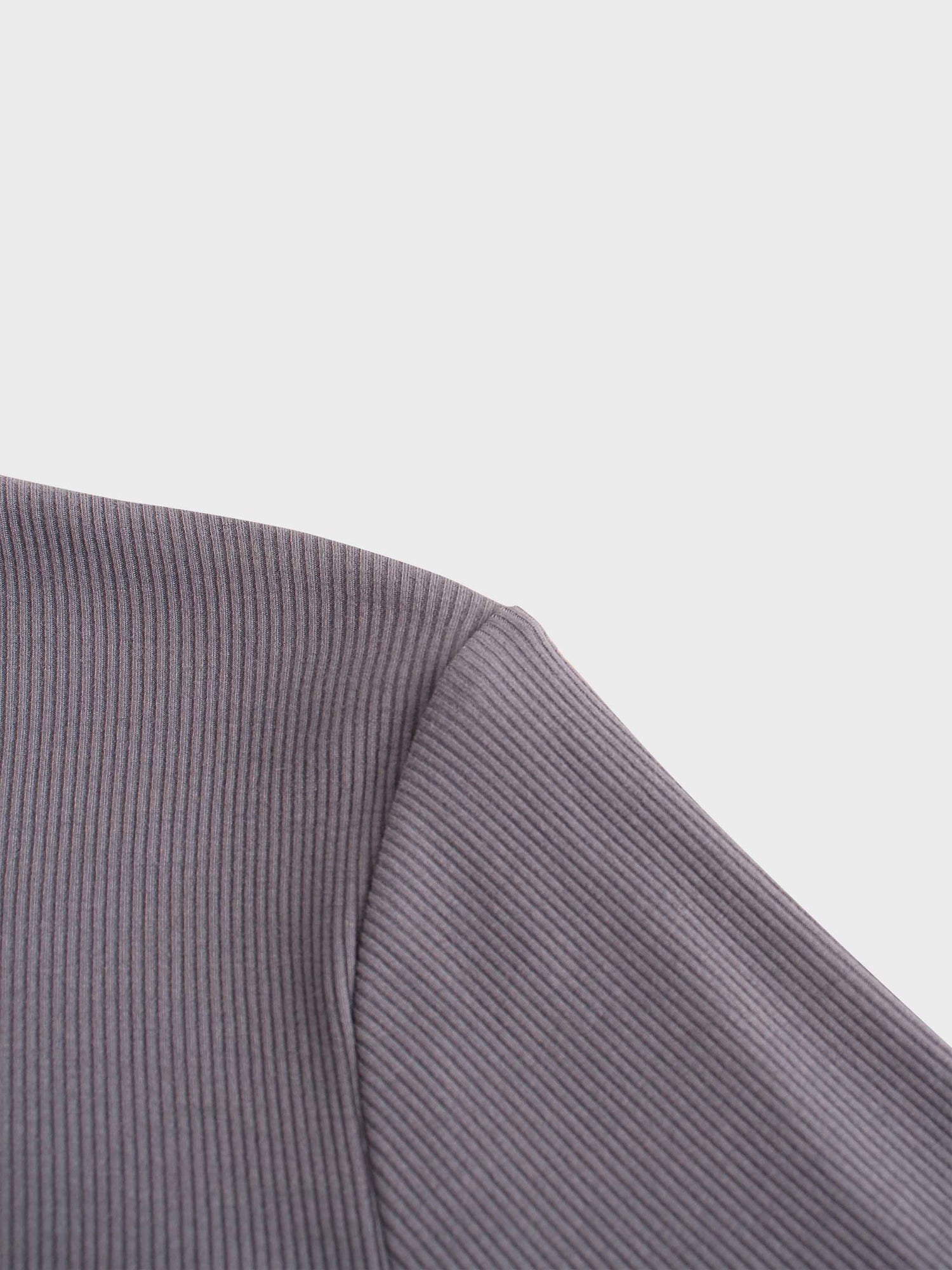 A close-up shot of the shoulder area of the ribbed garment. The image focuses on the seam where the sleeve is attached to the body of the shirt.