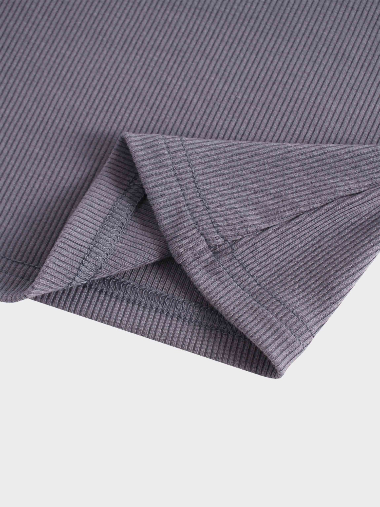 A detailed view of the hem of a garment, showing a small slit or vent on the side.