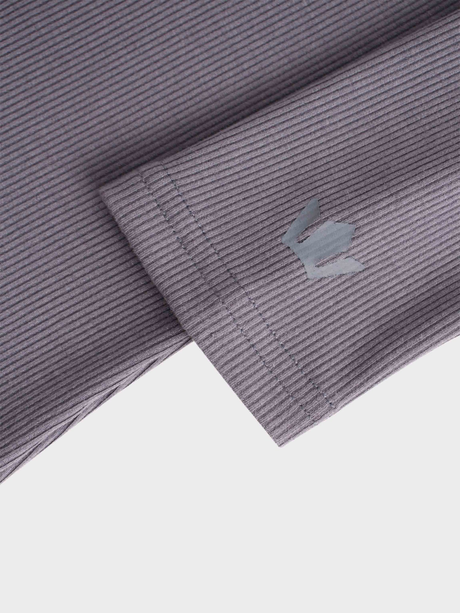 This is a close-up of what appears to be the sleeve or cuff of a garment. The purple, ribbed fabric has a neatly stitched hem and a small, gray, reflective logo on it.