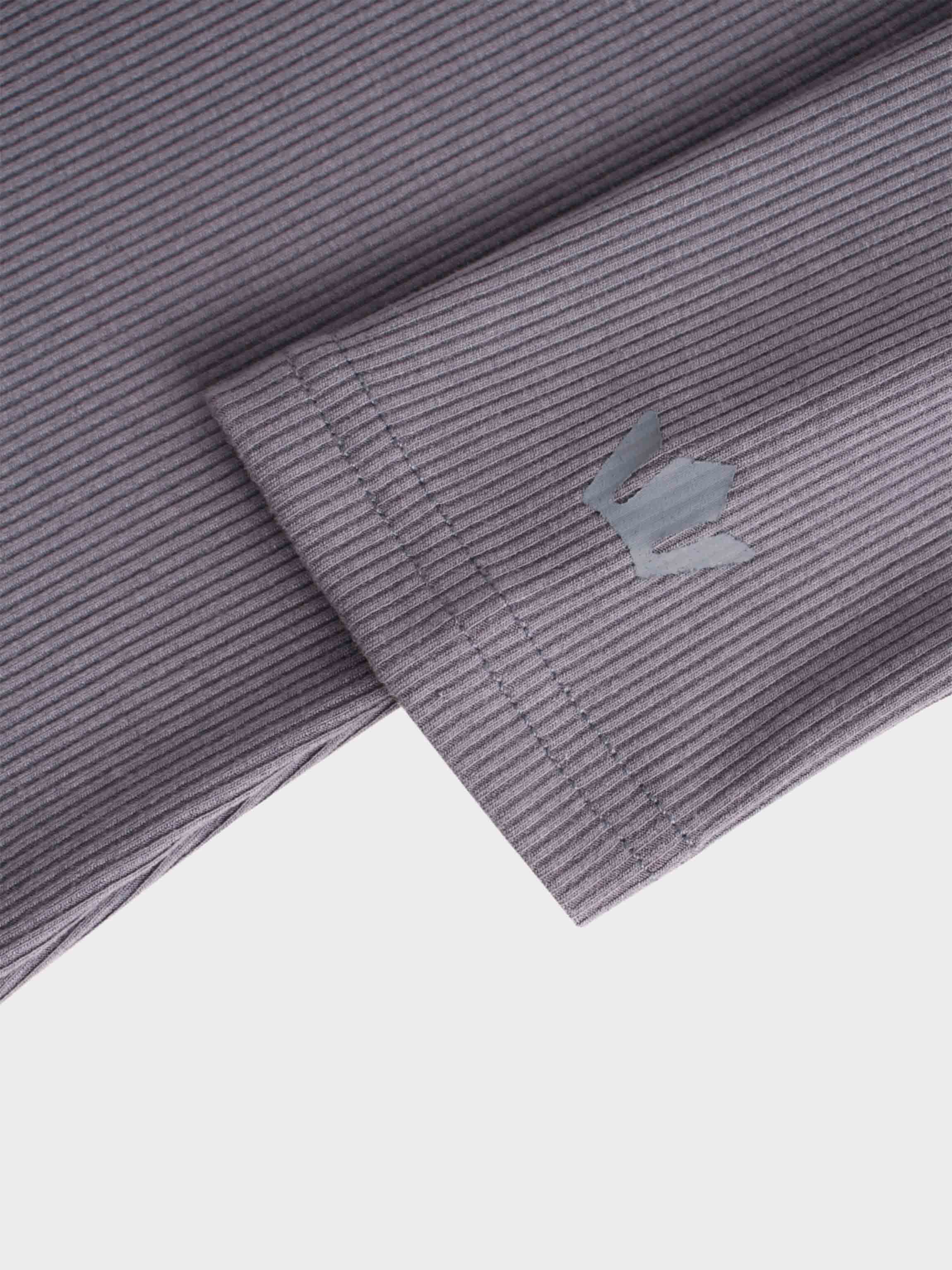 This is a close-up of what appears to be the sleeve or cuff of a garment. The purple, ribbed fabric has a neatly stitched hem and a small, gray, reflective logo on it.